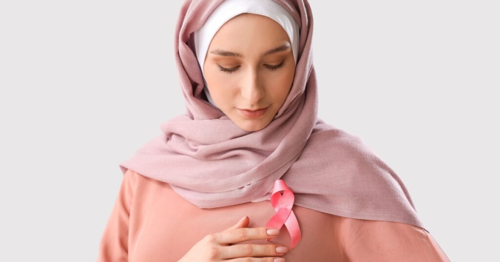 Muslim woman with pink ribbon on light background. Breast cancer awareness concept