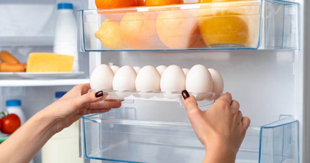 Female hand taking egg from a fridge