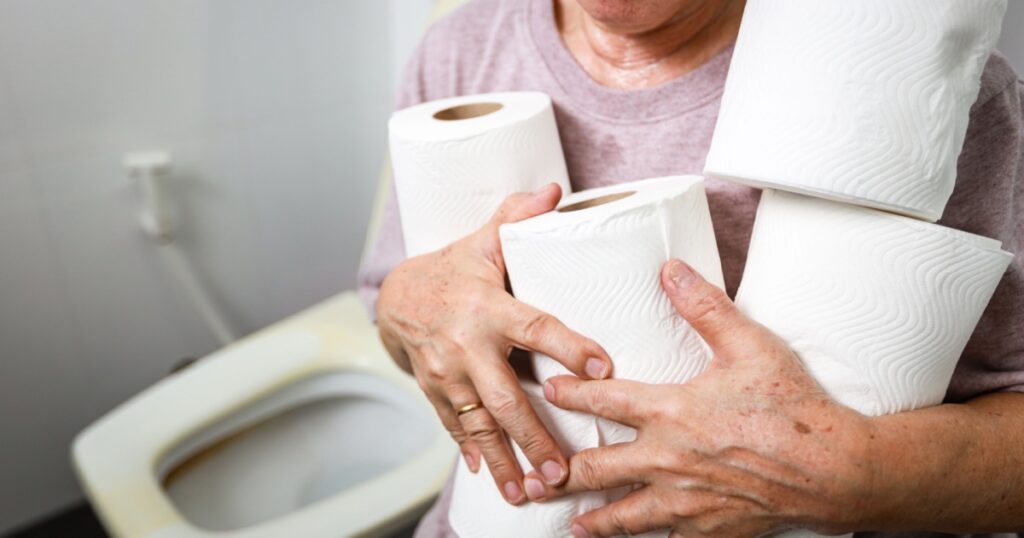 Senior woman carrying holding a lot of toilet paper in bathroom,many rolls of toilet paper for wiping,cleaning after urination or defecation,frequent urination problems or diarrhea in the old elderly