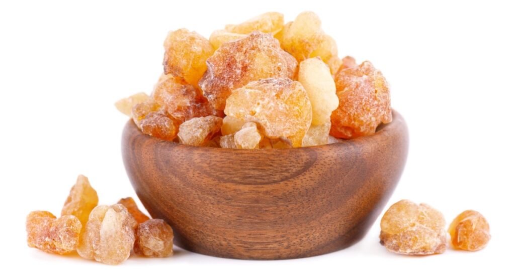 Frankincense resin in wooden bowl, isolated on white background. Pile of natural frankincense Olibanum. Incense