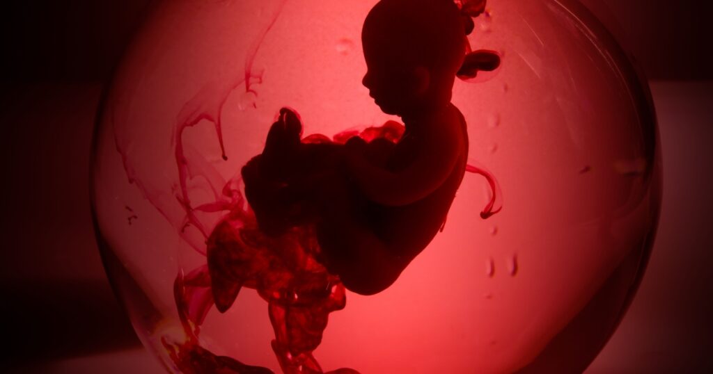 Abortion concept. Baby doll in the red blood looks like abortation.