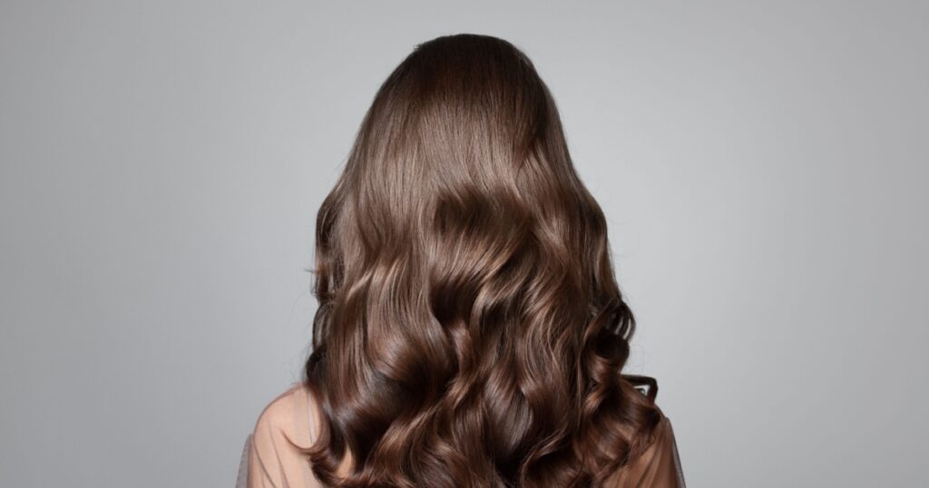 Portrait of a beautiful girl with luxurious curly long hair. Back view.