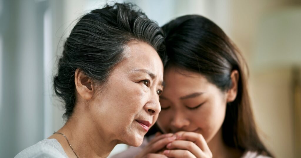 young asian adult daughter consoling senior mother living with mental illness