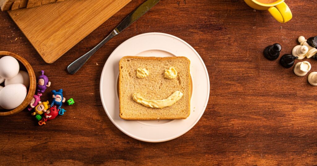 Top shot of Breakfast table, Bread, Slice, Butter, Bread with butter smile, Kids hand, breakfast decor, egg