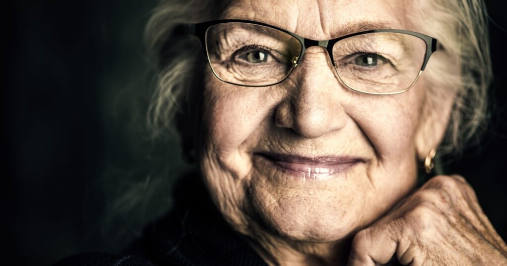 Portrait of a beautiful senior woman in elegant glasses smiling at camera.
