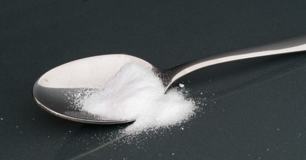White crystalline power. Artificial sweetener on spoon. Contains dextrose, fructose,sodium saccharin, acesulfame K.