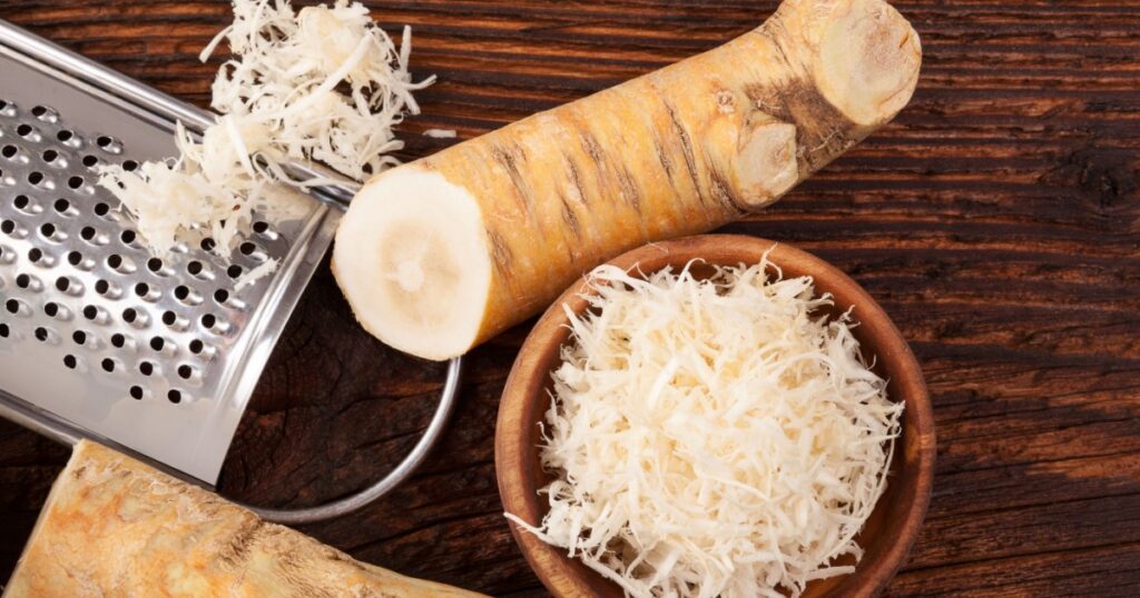 Fresh grated Horseradish roots on wooden table. Rustic style from above.