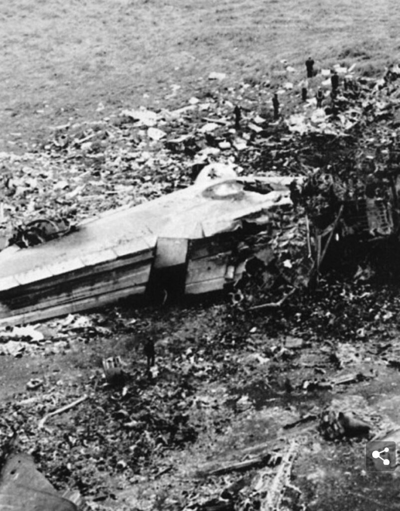 Black and white photo of plane remnants scattered in a field. 