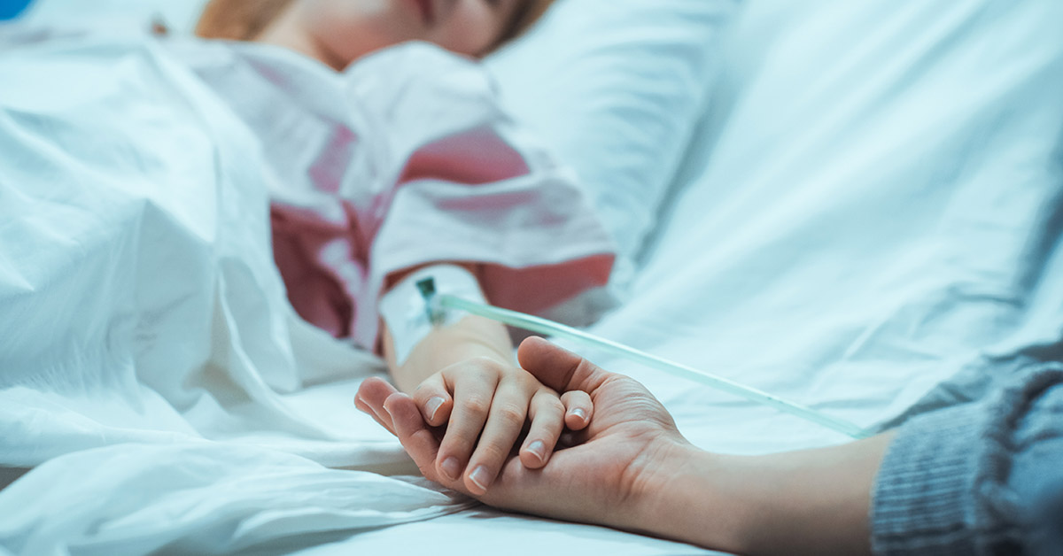 hand being held while laying in hospital bed