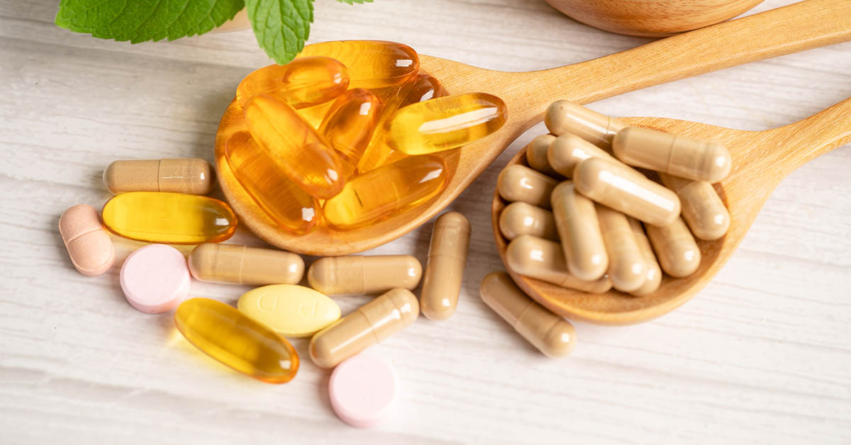 various dietary supplements on wooden spoon
