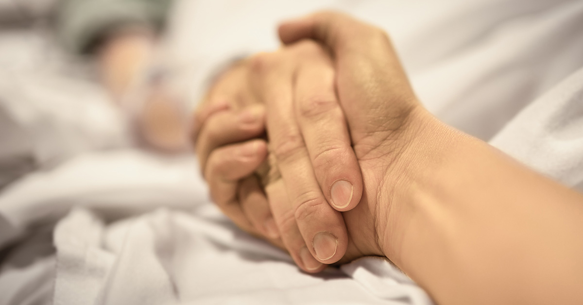 holding someone's hand on their death bed.