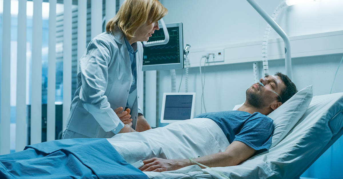 Doctor attending go man in hospital bed