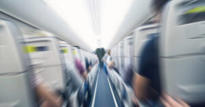 Woman Explains Turbulence to Help People Get Over Their Fear of Flying aisle inside a passenger jet. Image is blurred representing motion. Turbulence concept