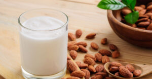 glass of almond milk with various almost scattered beside it