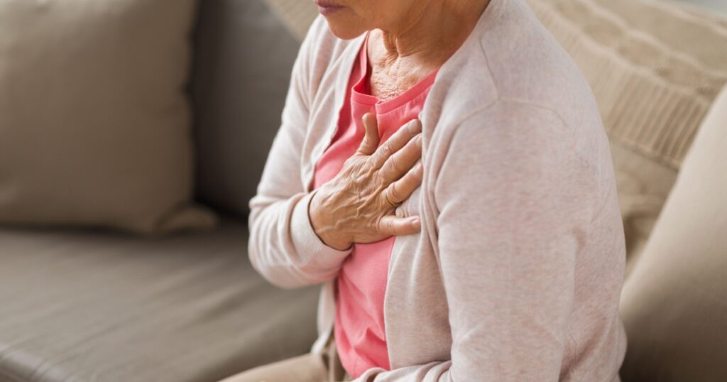 old age, health problem and people concept - close up of senior woman suffering from heartache at home