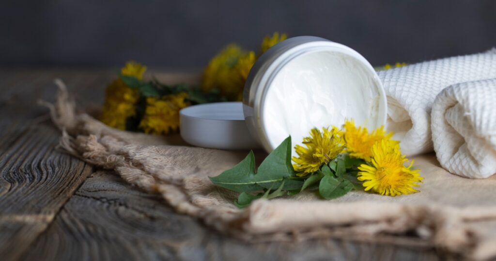 Cream with dandelion extract in a white plastic bottle on a wooden surface. Closeup