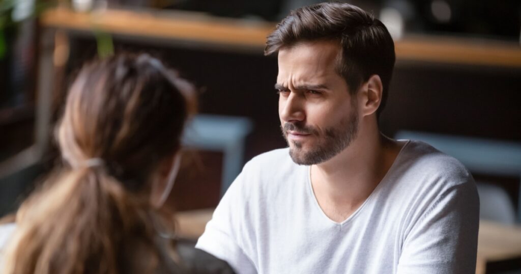 Doubting dissatisfied man looking at woman, bad first date concept, young couple sitting at table in cafe, talking, bad first impression, new acquaintance in public place, unpleasant