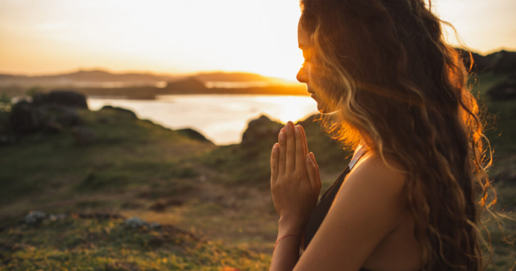 Woman praying alone at sunrise.