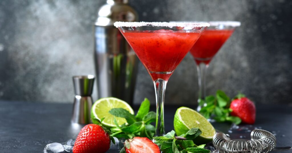 Cold summer strawberry cocktail with lime and mint ( mojito, margarita, rossini,daiquiri ) in a martini glasses on a dark slate, stone or concrete background..