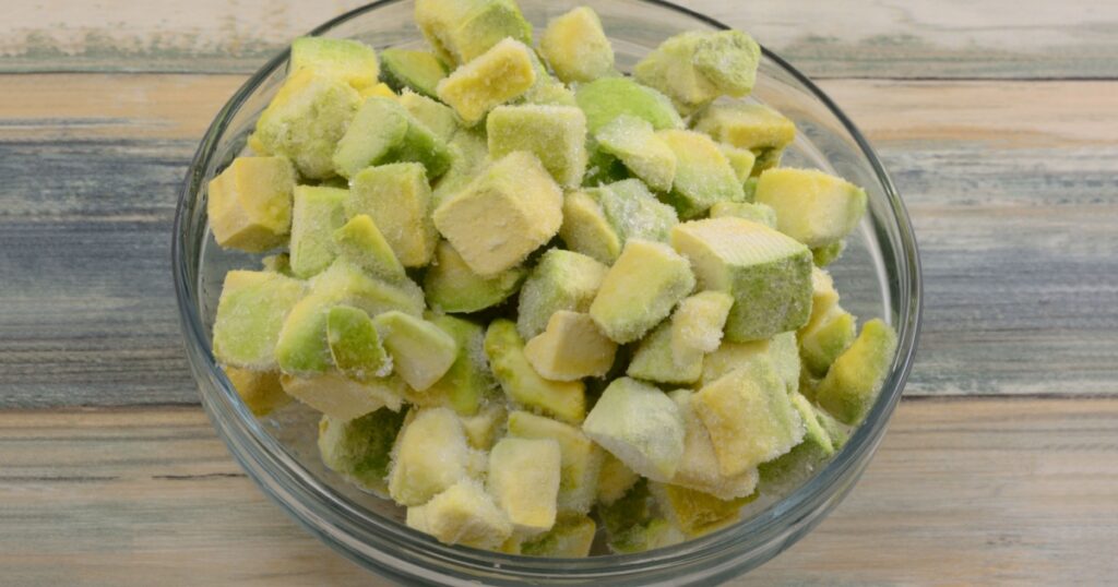 Frozen avocado chunks thawing in glass ingredient bowl on table