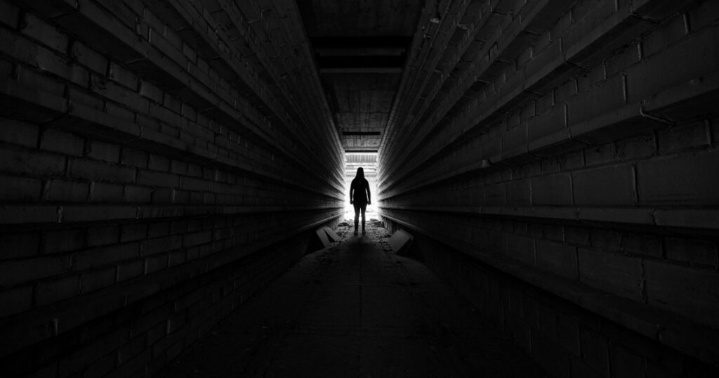 Person standing in light at the end of tunnel, silhouette