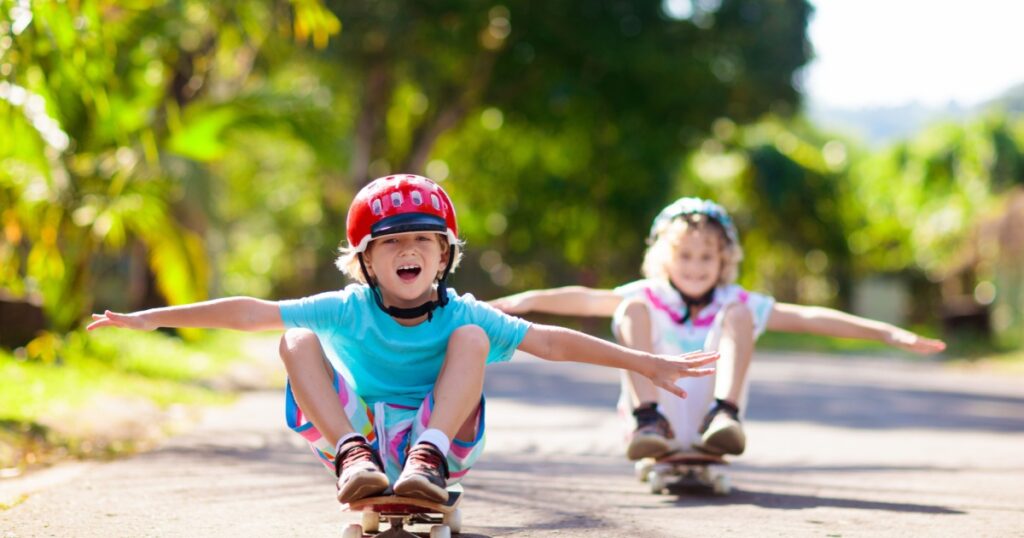 Kid with skateboard. Child riding skate board. Healthy sport and outdoor activity for school kids in summer. Sports fun. Helmet for safe exercise. Boy skater in sunny park. Children training.