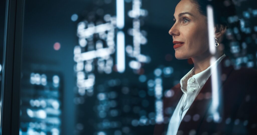 Successful Businesswoman in Stylish Suit Working on Top Floor Office Overlooking Night City. High Achievement Female CEO of Humanitarian Investment Fund, Human Face of Sustainable Corporate Governance