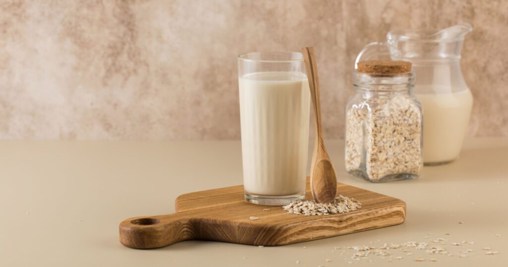 A glass of oat milk, a jug and oat flakes. The concept of alternative lactose-free dairy products. Copy space.