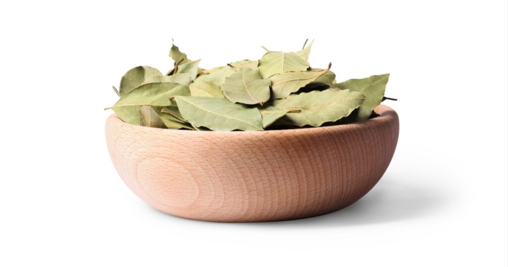 Aromatic bay leaves in wooden bowl on white background