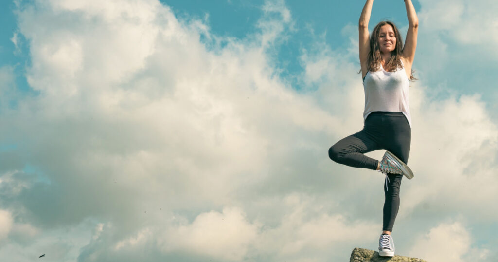 A beautiful woman practices yoga and meditates on a mountain top. Strong and independent women - concept.