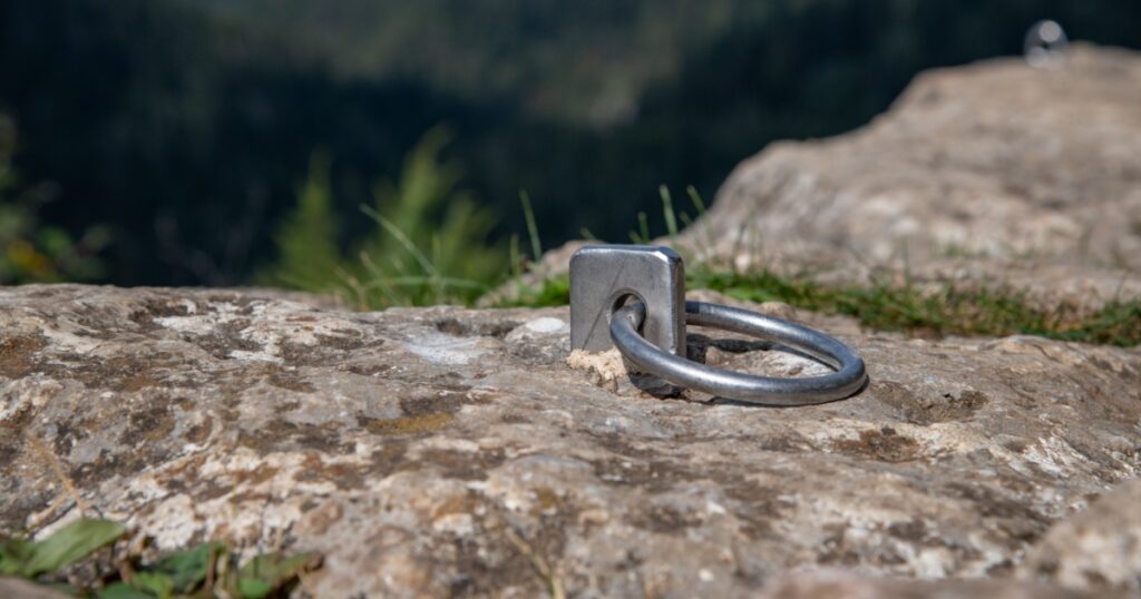 Fixed anchor points with chains and rings on natural climbing wall.