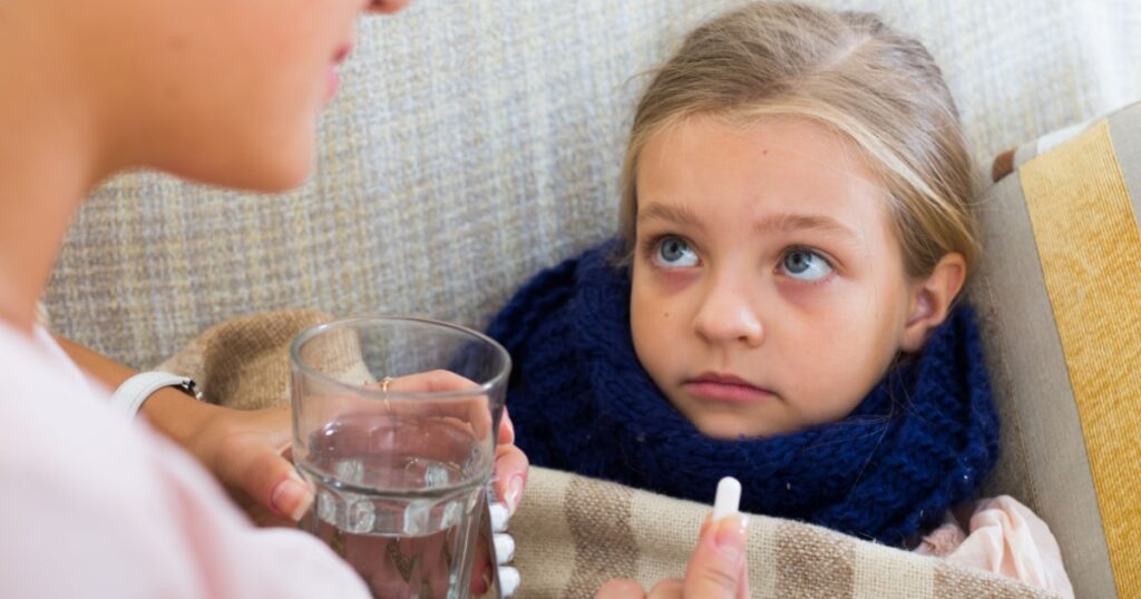 Sick little girl taking medication from worried mother
