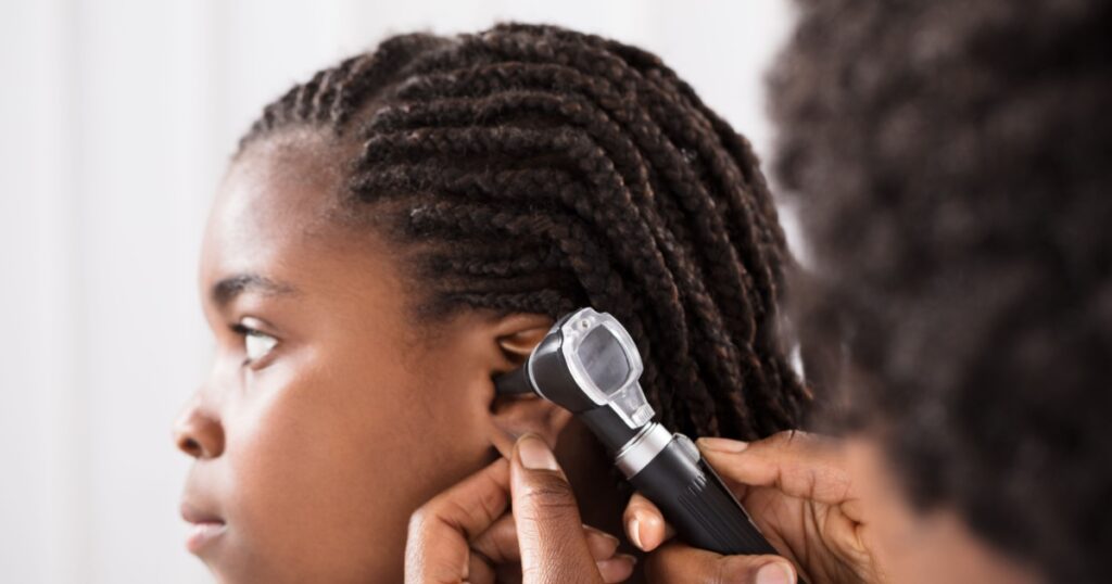 Doctor Using Otoscope Instrument To Check Girl's Ear In Hospital
