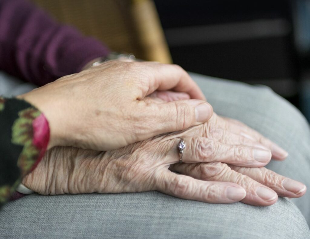 Elderly couple holds hands. 