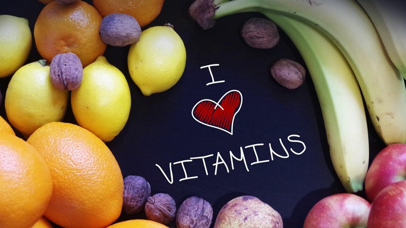 Assortment of fruits around a sign that says I heart vitamins. 