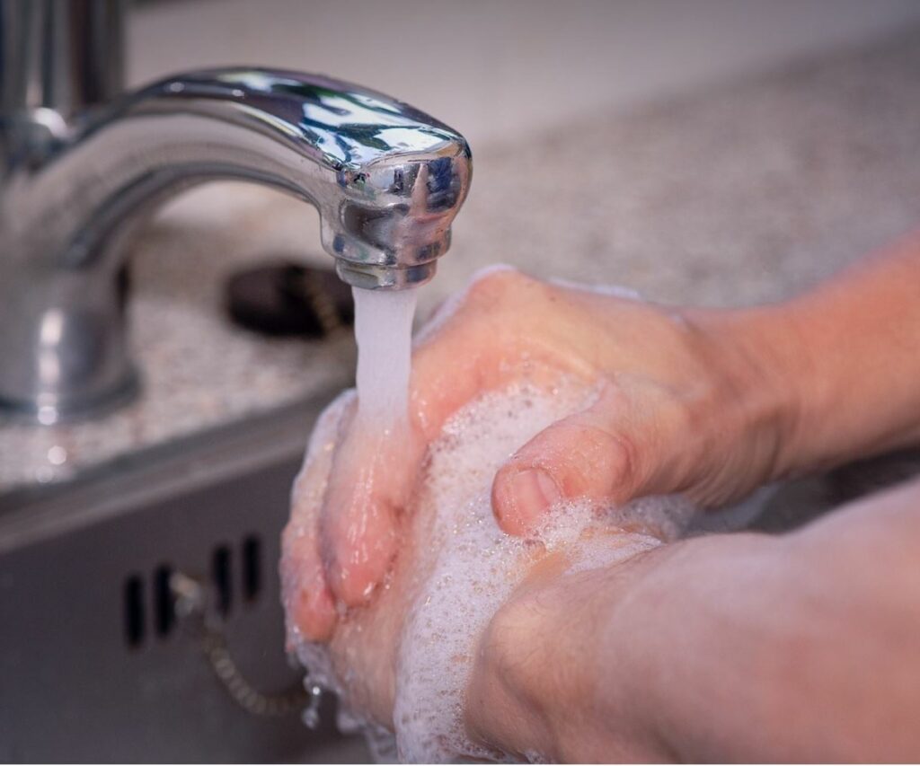 Close up of hands being washed in the sink. 