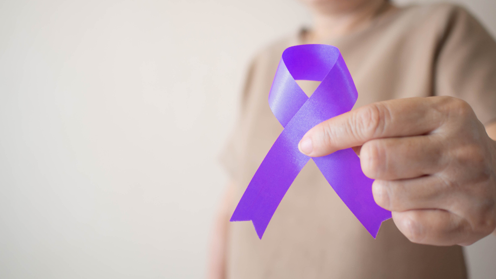 Elderly woman holding purple ribbon awareness w/ copy space. Symbol is used to raise awareness for Alzheimer's disease, elder abuse, epilepsy, pancreatic cancer, thyroid cancer and lupus. Close up.