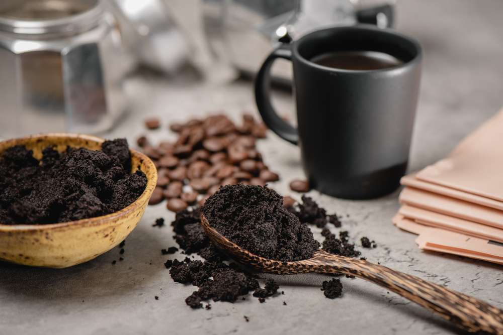 closeup used coffee grounds in wooden spoon
