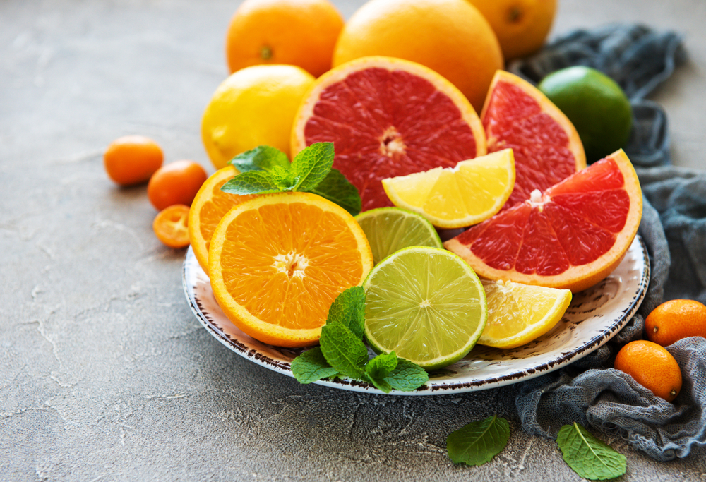 Plate with citrus fresh fruits on a concrete background