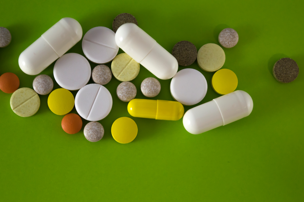 Various pills and capsules. Drug interactions concept. Drug addiction and abuse. Pharmacy. Yellow, grey, white, red, green medications. Mixing medicine.