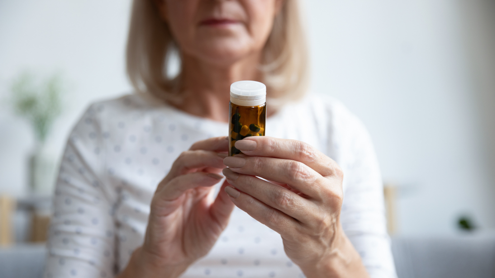 Mature woman in glasses hold bottle with pills read medicine instruction on packaging before take meds, senior female retiree in spectacles thinking of medication treatment, elderly healthcare concept