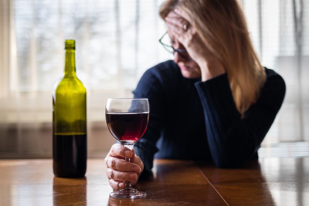 Lonely sad woman drinking red wine at home. Depression and sadness concept. Alcohol abuse social problem. 