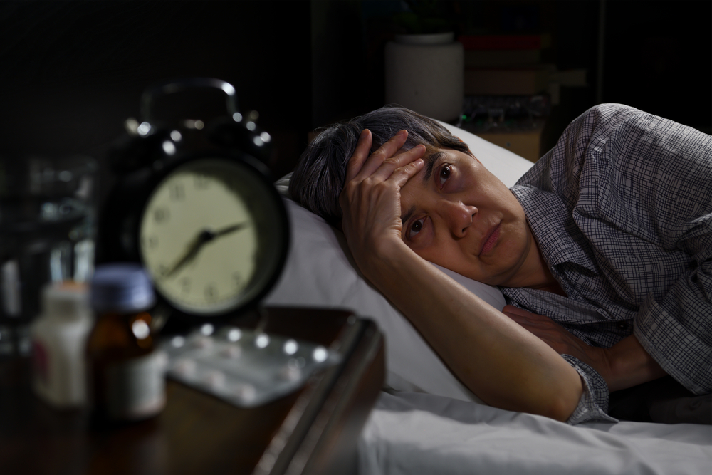 Depressed senior woman lying in bed cannot sleep from insomnia
