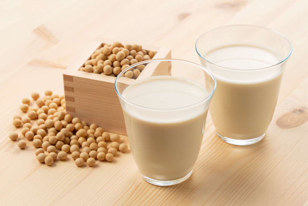 Soy milk in a glass on a wooden background. Soybeans in a masu in the background