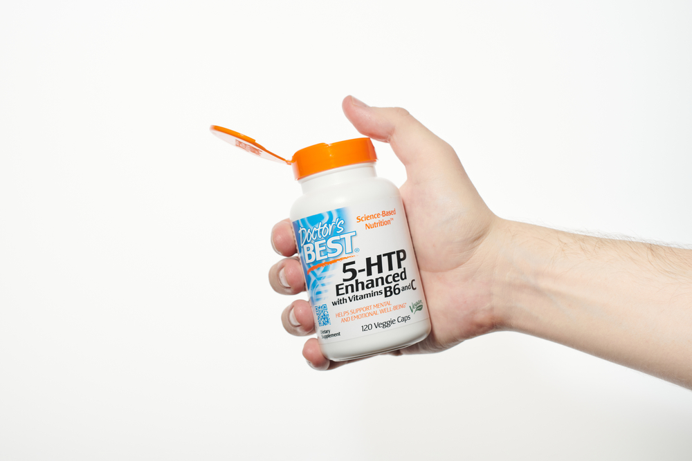 Doctors Best 5-HTP Enhanced in hand. 5HTP opened bottle with vitamin B6 and vitamin C. Veggie Caps, Non-GMO, Vegan, Gluten Free, Soy Free, Isolated white background - KALININGRAD, RUSSIA - 03.07.2020
