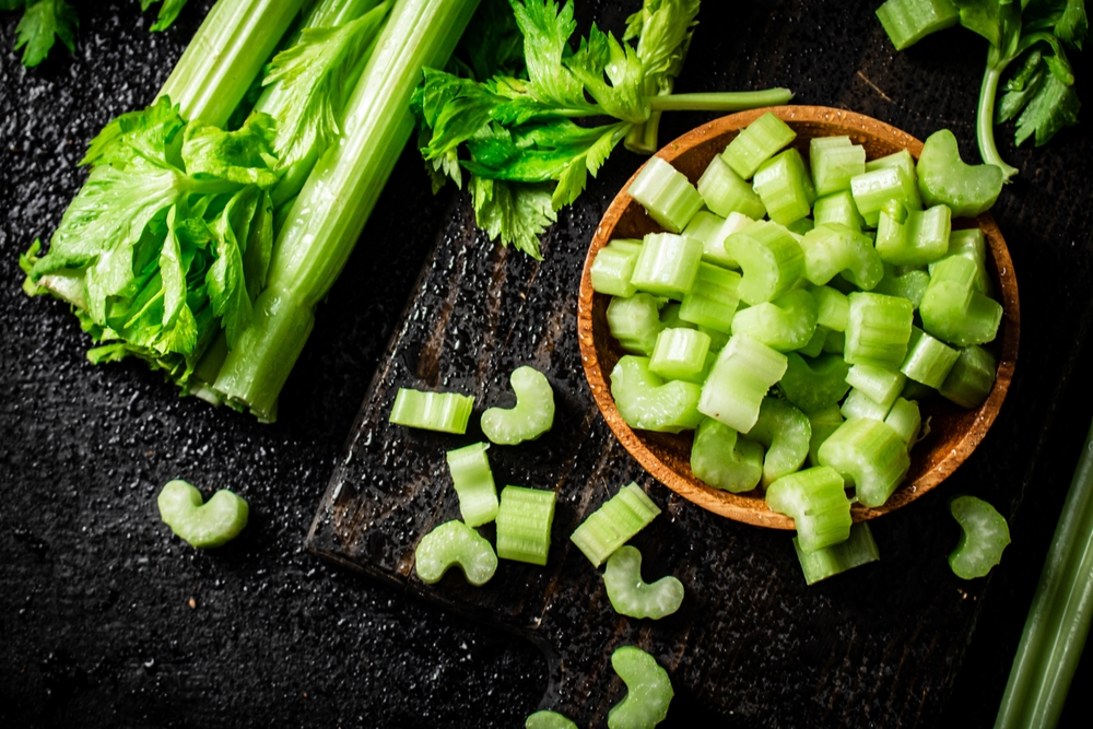 Pieces of celery in a wooden plate on the table. On a black background. High quality photo