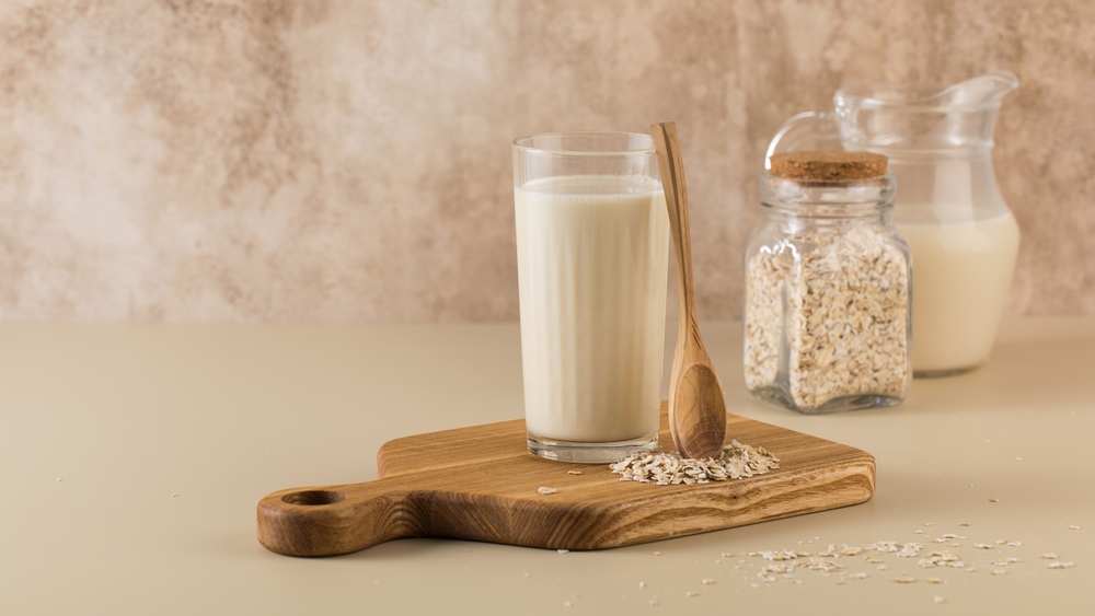 A glass of oat milk, a jug and oat flakes. The concept of alternative lactose-free dairy products. Copy space.