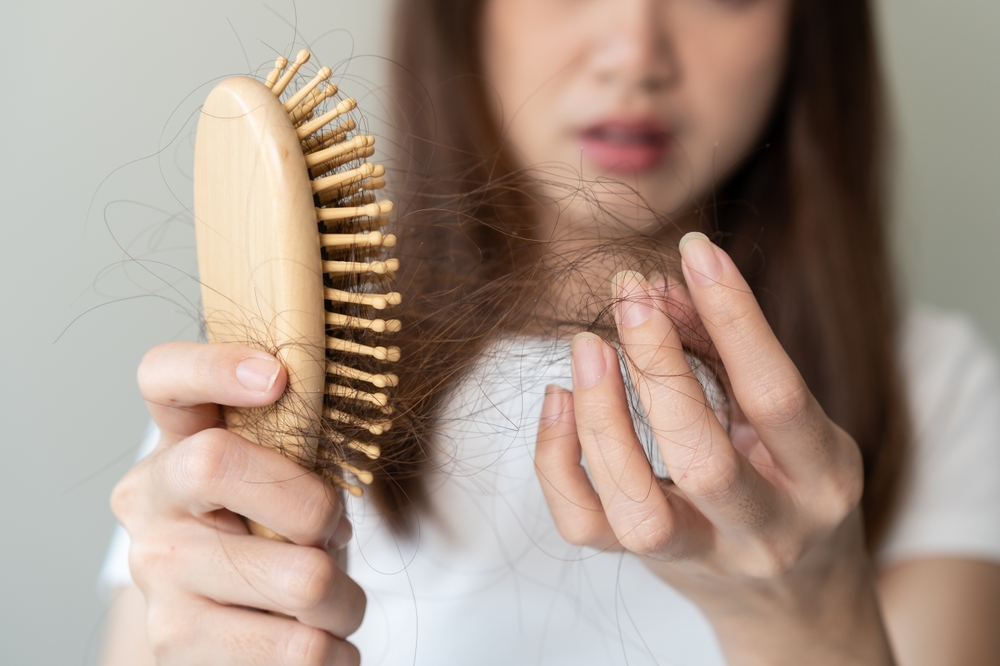 Close-up young woman brushing her hair and have many hair loss on the comb