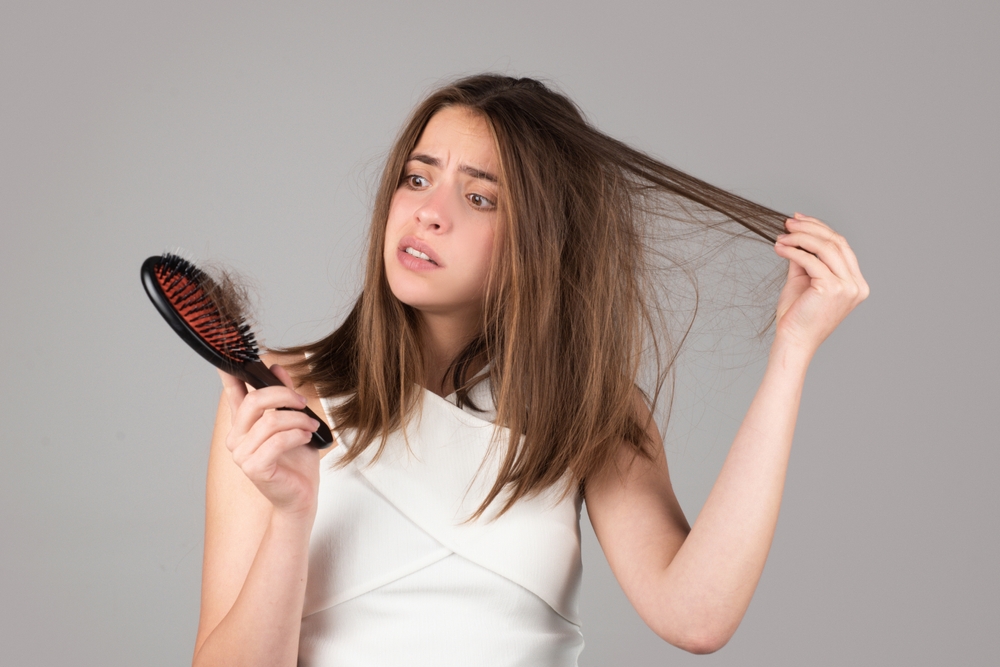 Woman hand holding comb with serious hair loss problem for health care shampoo.
