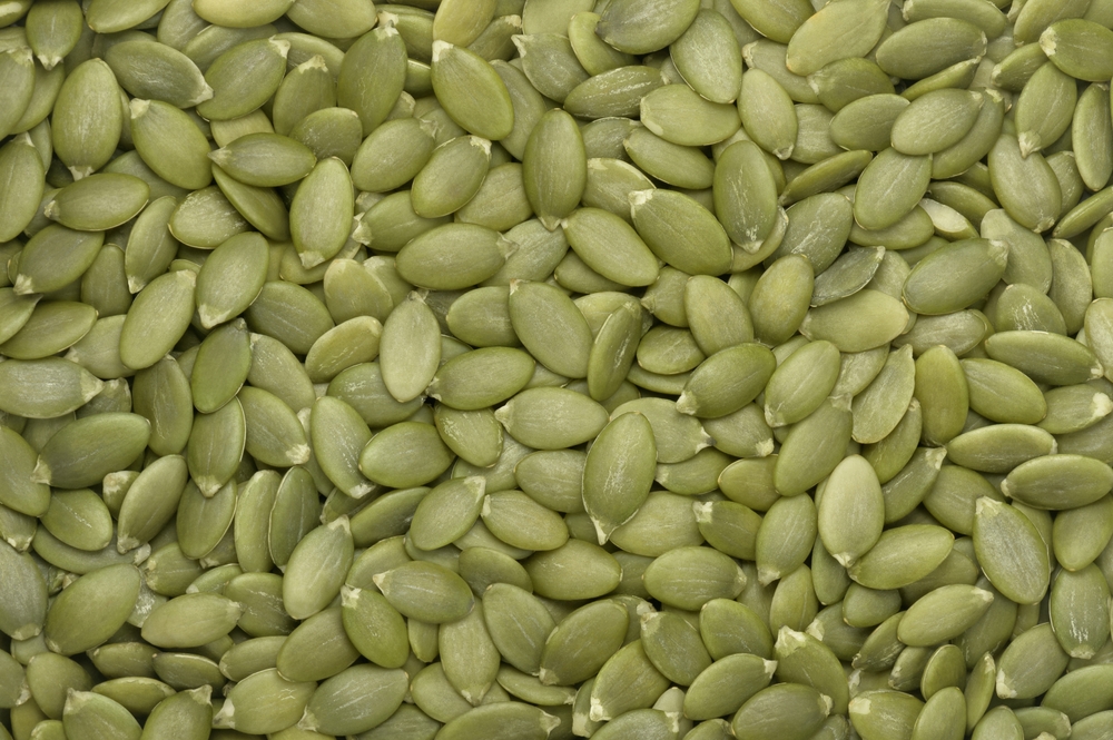 Green pumpkin seeds background. Top view. Flat lay. Texture element for package and marketing materials design